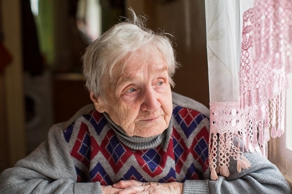 senior woman sitting at kitchen table looking out her window