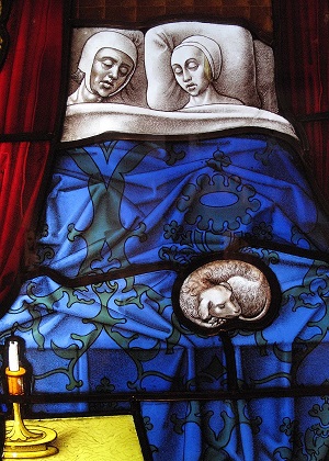 Medieval stained glass church window panel showing a married couple sleeping