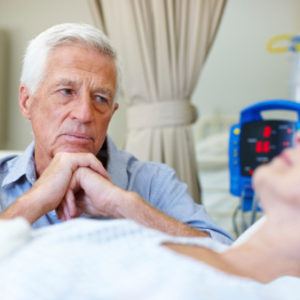 An elderly man looking concerned over his wife's condition while in the hospital