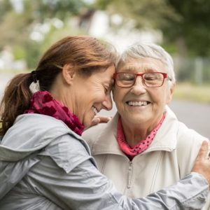 Happy senior woman and caregiver walking outdoors