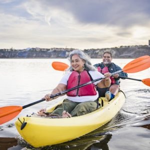 Older adult couple kayaking on a lake on partly cloudy day