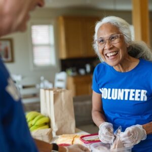 Cheerful mature woman smiles and talks with other volunteers
